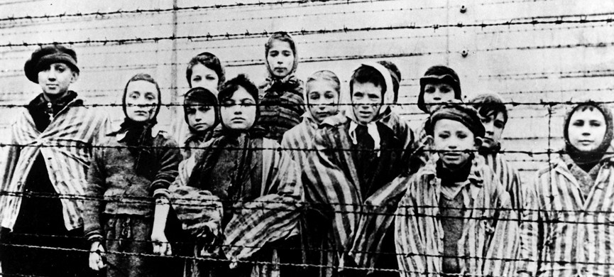 FILE — A picture taken just after the liberation by the Soviet army in January, 1945, shows a group of children wearing concentration camp uniforms behind barbed wire fencing in the Auschwitz Nazi concentration camp. One of the black-uniformed men on the ramp where people arrived was likely SS guard Oskar Groening who goes on trial Tuesday, April 21, 2015 in a state court in the northern city of Lueneburg on 300,000 counts of accessory to murder. (AP Photo/FILE)