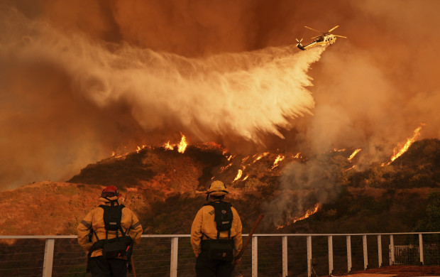 <p>Firefighters watch as water is dropped on the Palisades Fire in Mandeville Canyon Saturday, Jan. 11, 2025, in Los Angeles. (AP Photo/Jae C. Hong)</p>